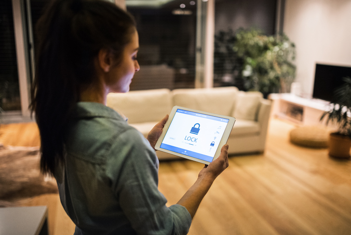 A woman holding a tablet with smart home screen.